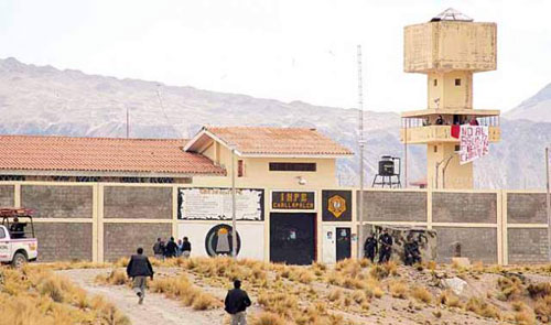 Challapalca, es un abominable establecimiento penitenciario de castigo. En primer plano, el <em>ichu</em>, pasto natural que alimenta a las alpacas. En el torreón de vigilancia, los amotinados y un cartel con letras rojas: no más abusos, cierre de Challapalca