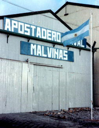 Imagen 1. Fachada del galpón donde funcionó el Apostadero Naval Malvinas durante el conflicto (fotografía de mayo de 1982). Fuente: <a href=