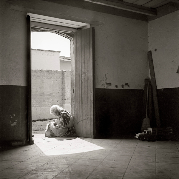 Anciana sentada en el umbral de la casa de un pueblo (1950)